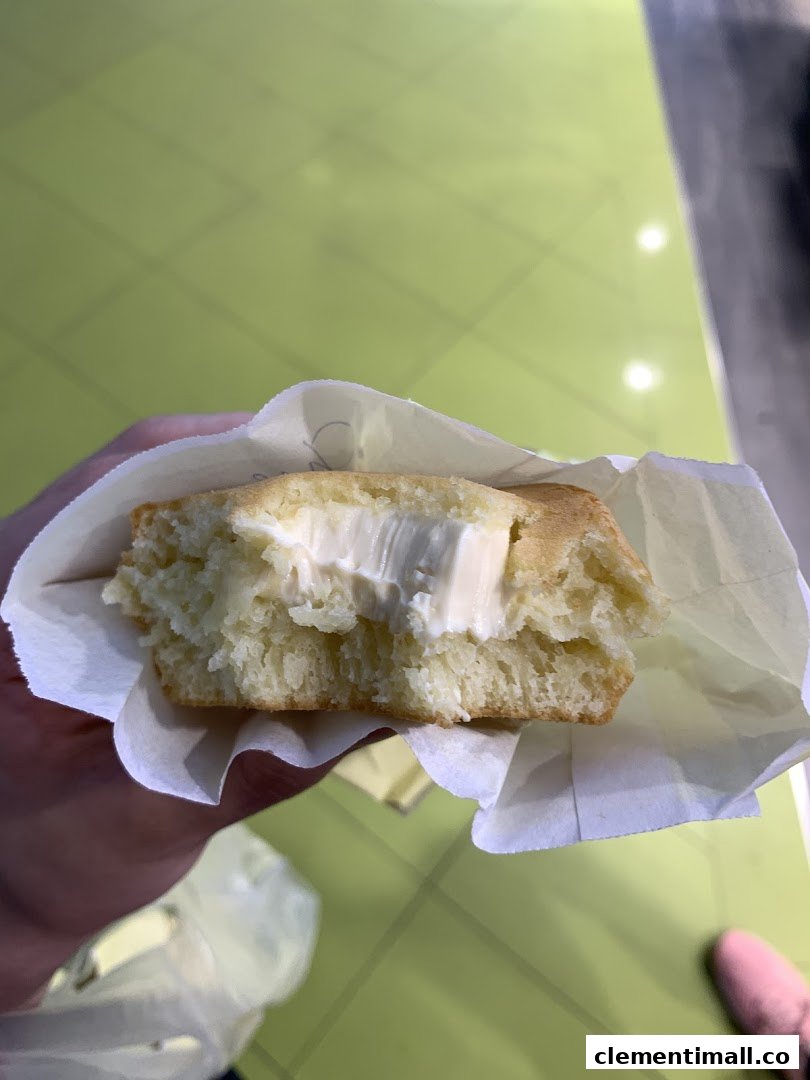 A fluffy pancake filled with creamy white filling, held in a paper wrapper.