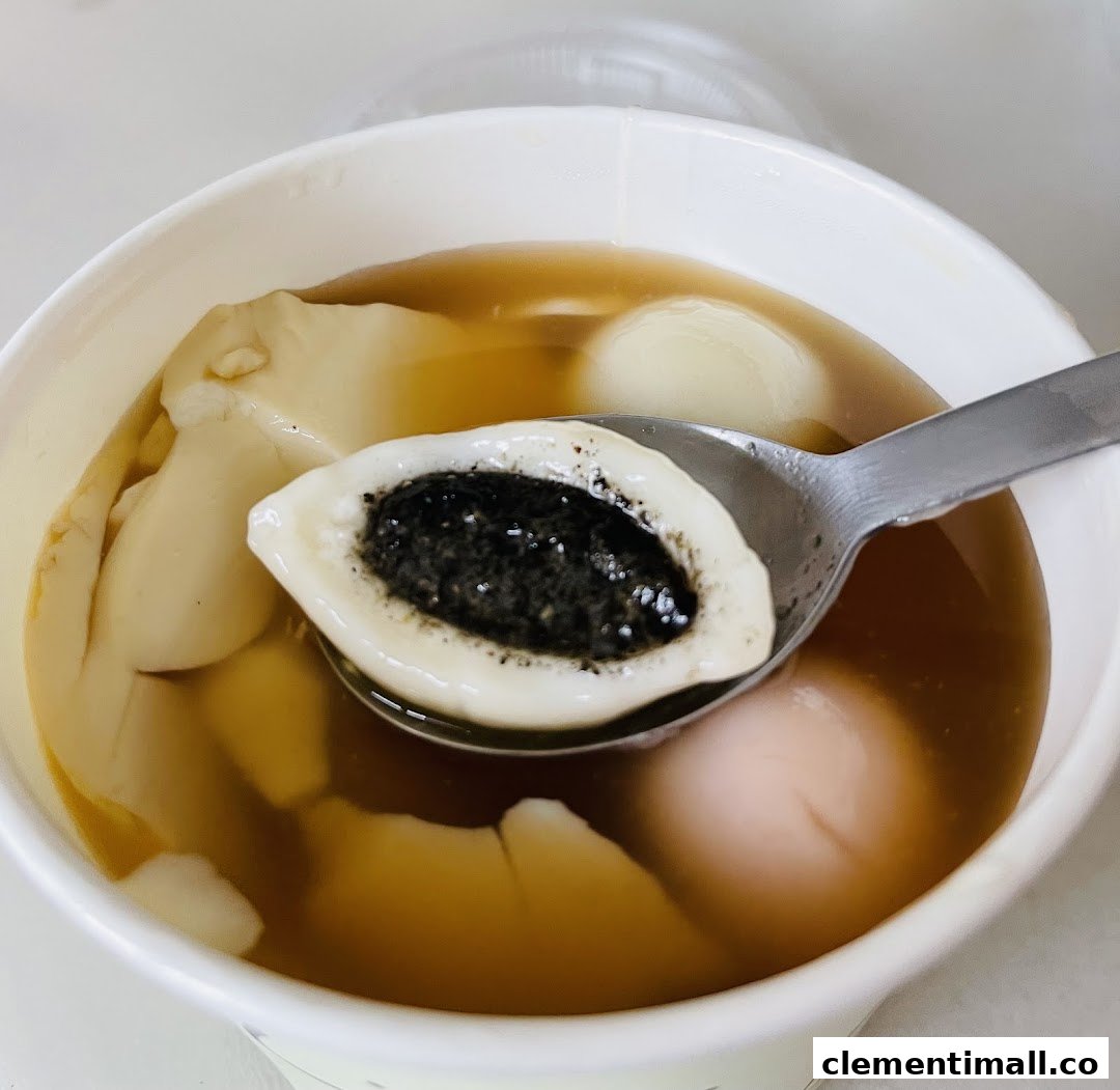 A close-up of a Mr Bean dessert featuring smooth tofu pudding and glutinous rice balls, one with black sesame filling.