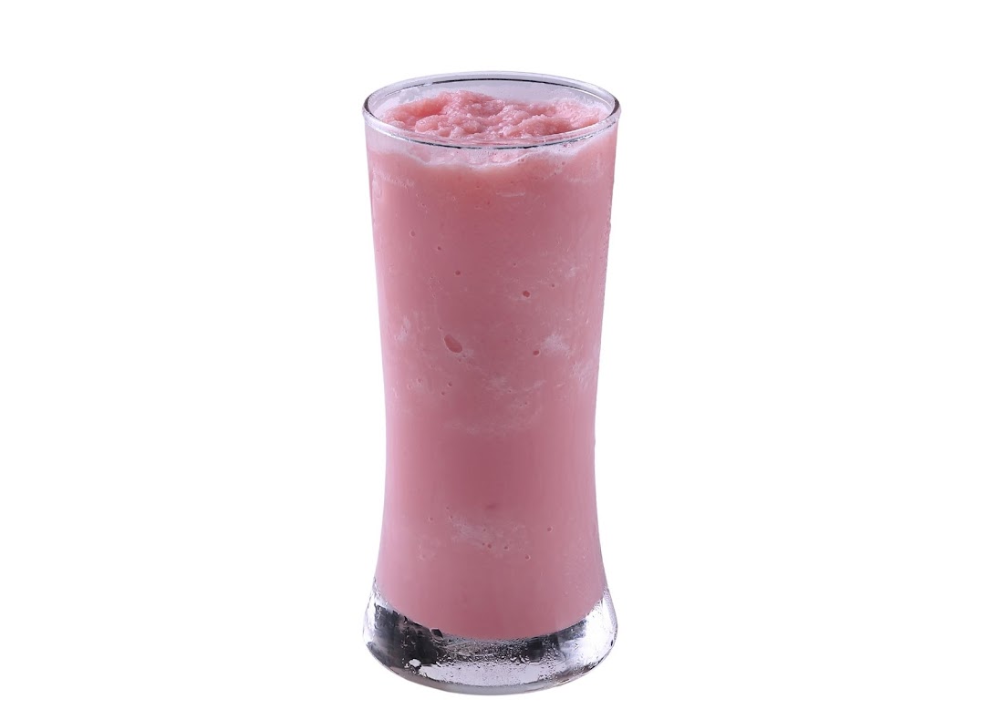 A tall glass filled with a refreshing pink blended drink, likely a smoothie or milkshake.