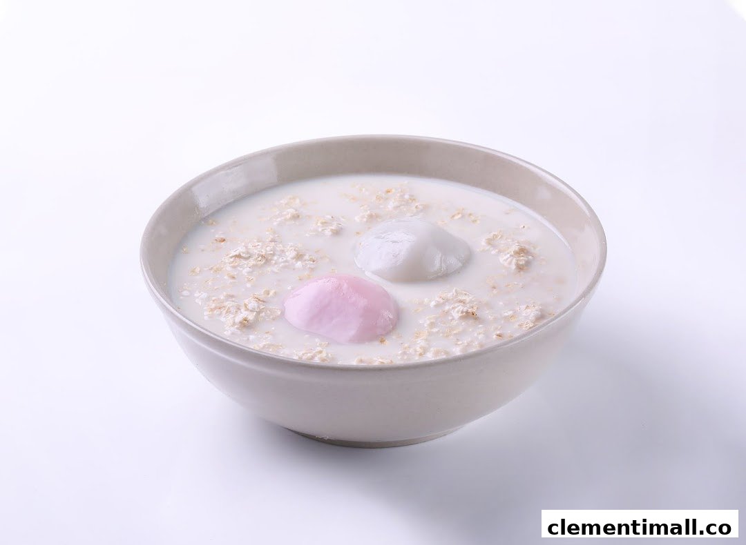 A bowl of creamy oatmeal or cereal with two colorful mochi-like dumplings.