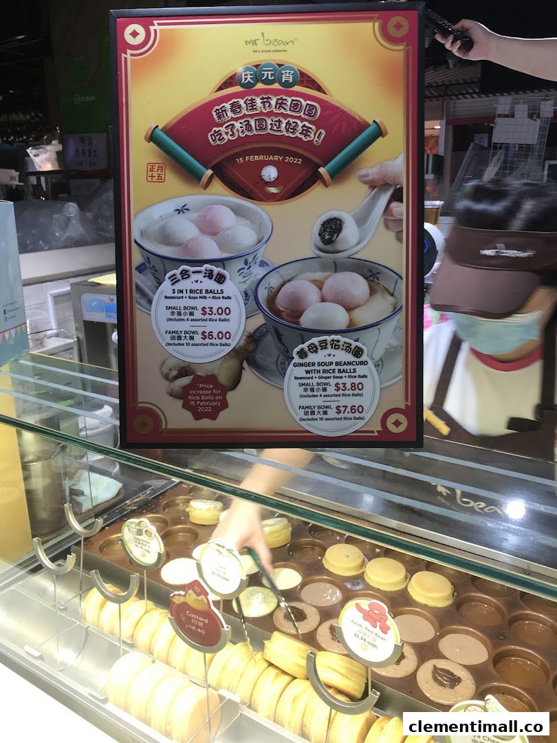 A vibrant menu board for Mr Bean featuring rice balls and beancurd, alongside a display of freshly made pastries.