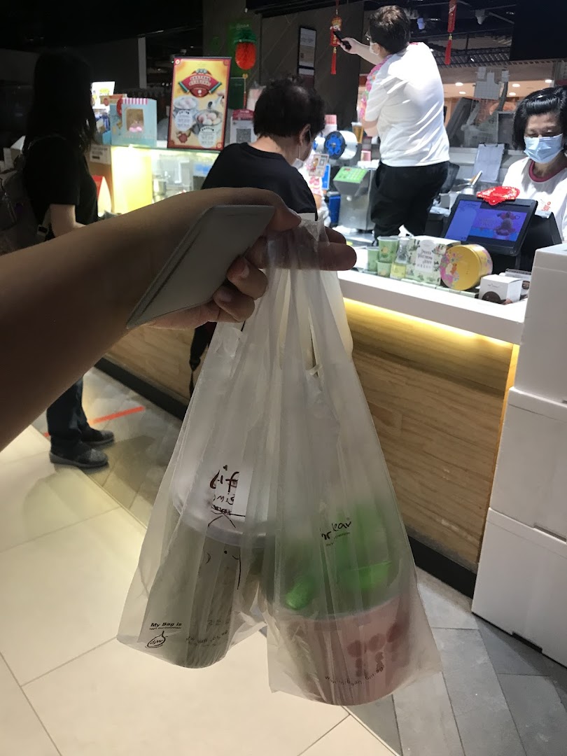 A customer holds a bag with two drinks from Mr Bean, with the shop counter and staff visible in the background.