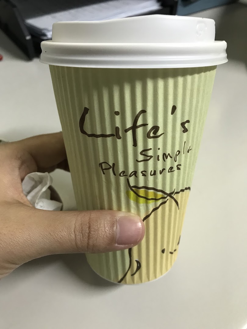 A hand holds a Mr Bean branded coffee cup with 'Life's Simple Pleasures' text.
