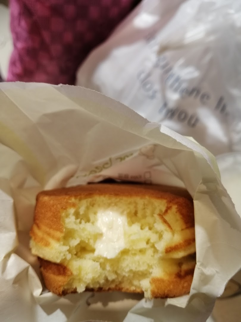 A delicious Mr Bean pancake with creamy filling, partially eaten and held in a paper bag.