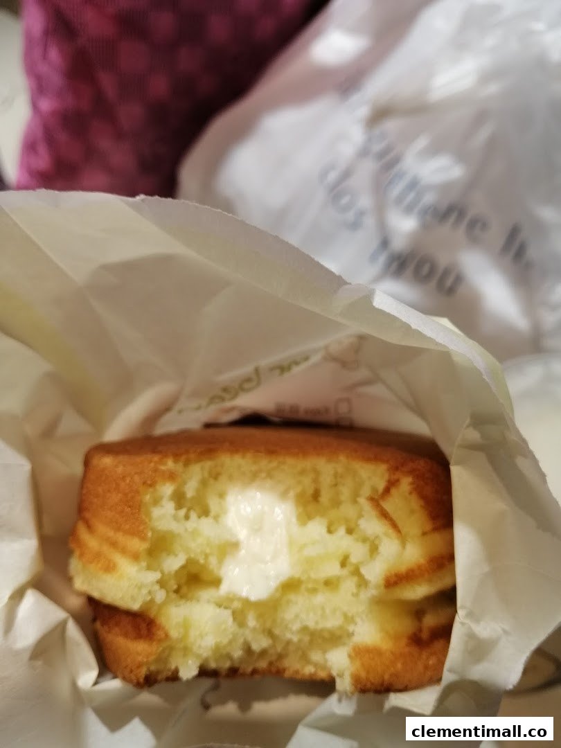 A delicious Mr Bean pancake with creamy filling, partially eaten and held in a paper bag.