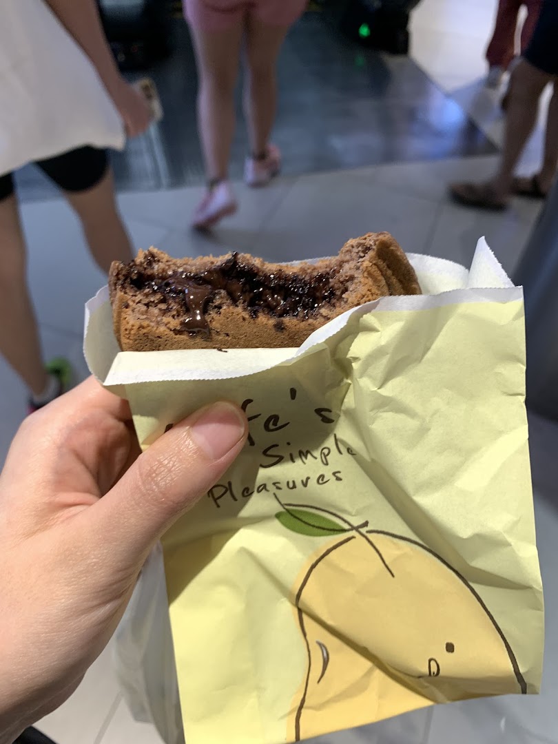 A hand holds a partially eaten chocolate-filled waffle from Mr Bean in a yellow wrapper.