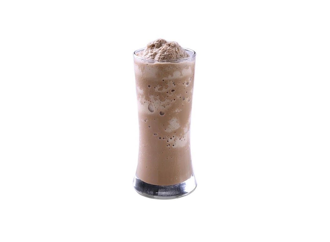 A tall glass of chocolate or coffee-flavored blended drink with a frothy top.
