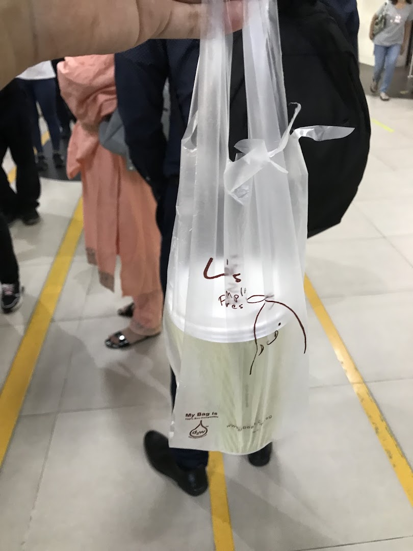 A person holds a Mr Bean takeaway cup in a branded plastic bag, likely after a purchase.