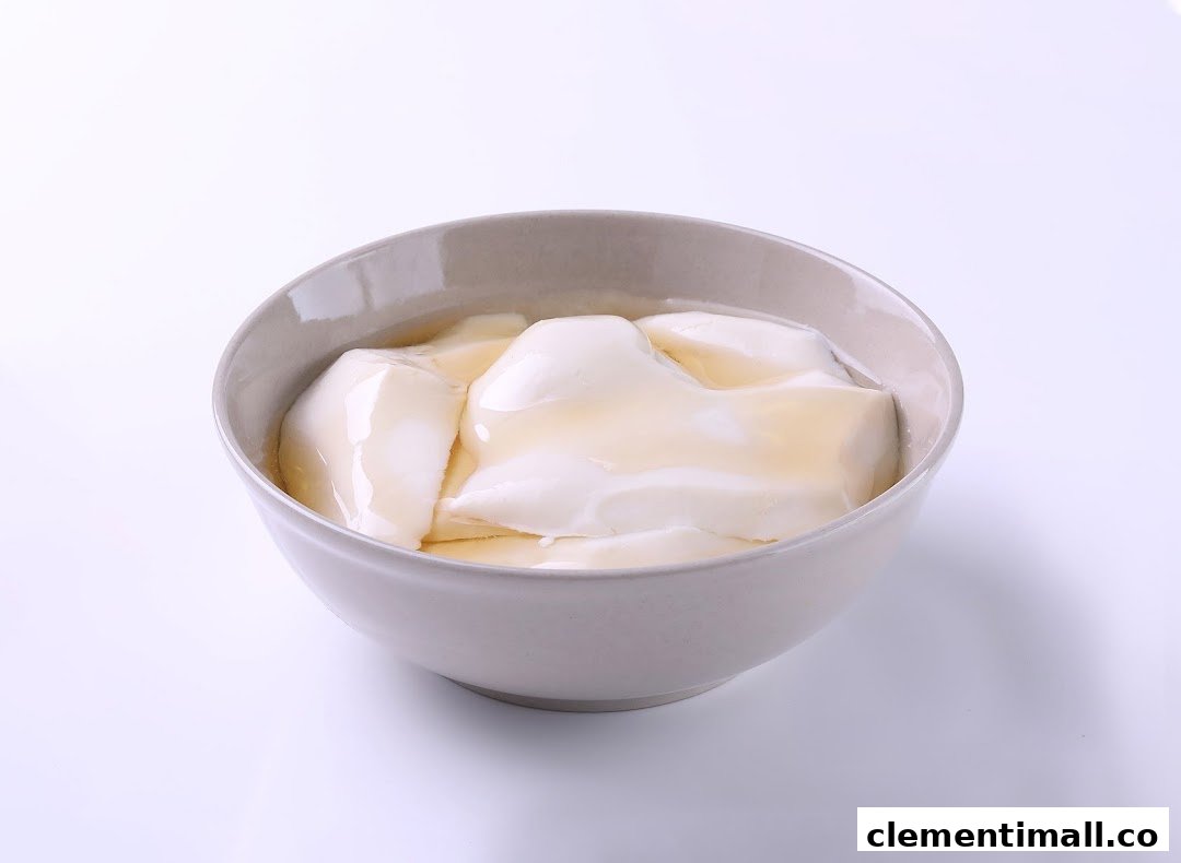 A bowl of smooth tofu pudding with a drizzle of syrup on a white background.
