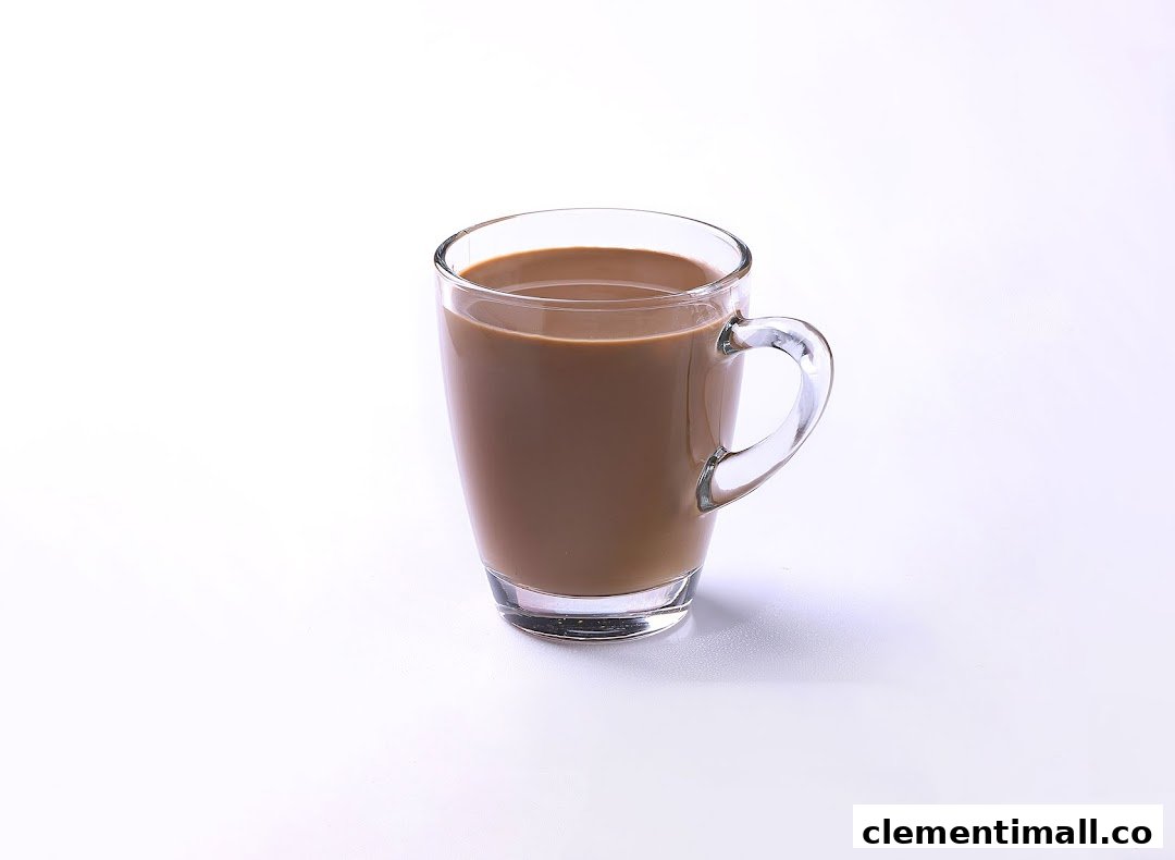 A clear glass mug filled with a light brown beverage, possibly coffee or soy milk, on a white background.
