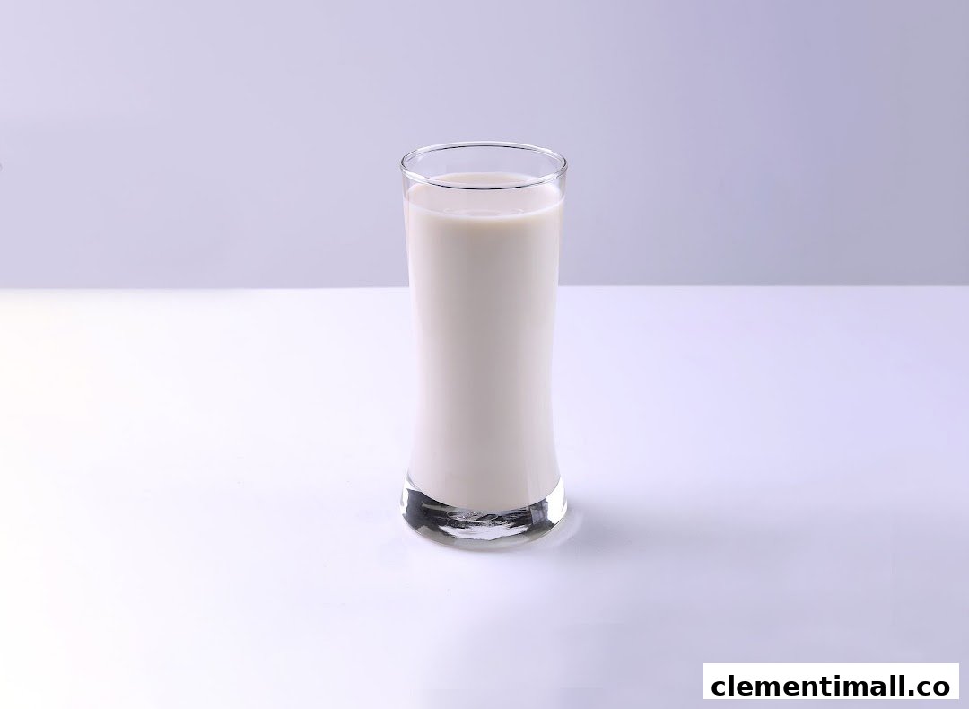 A tall glass filled with creamy white soy milk on a clean white surface.