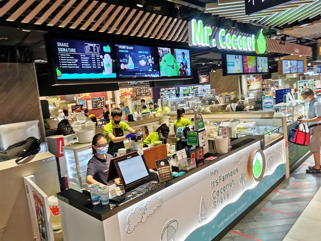 Mr Coconut shop counter with staff preparing drinks and digital menu boards displayed.