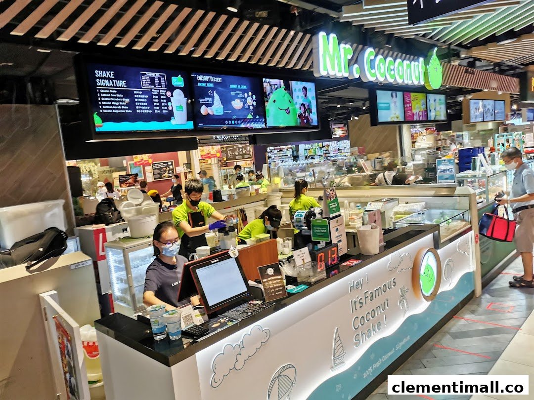 Mr Coconut shop counter with staff preparing drinks and digital menu boards displayed.