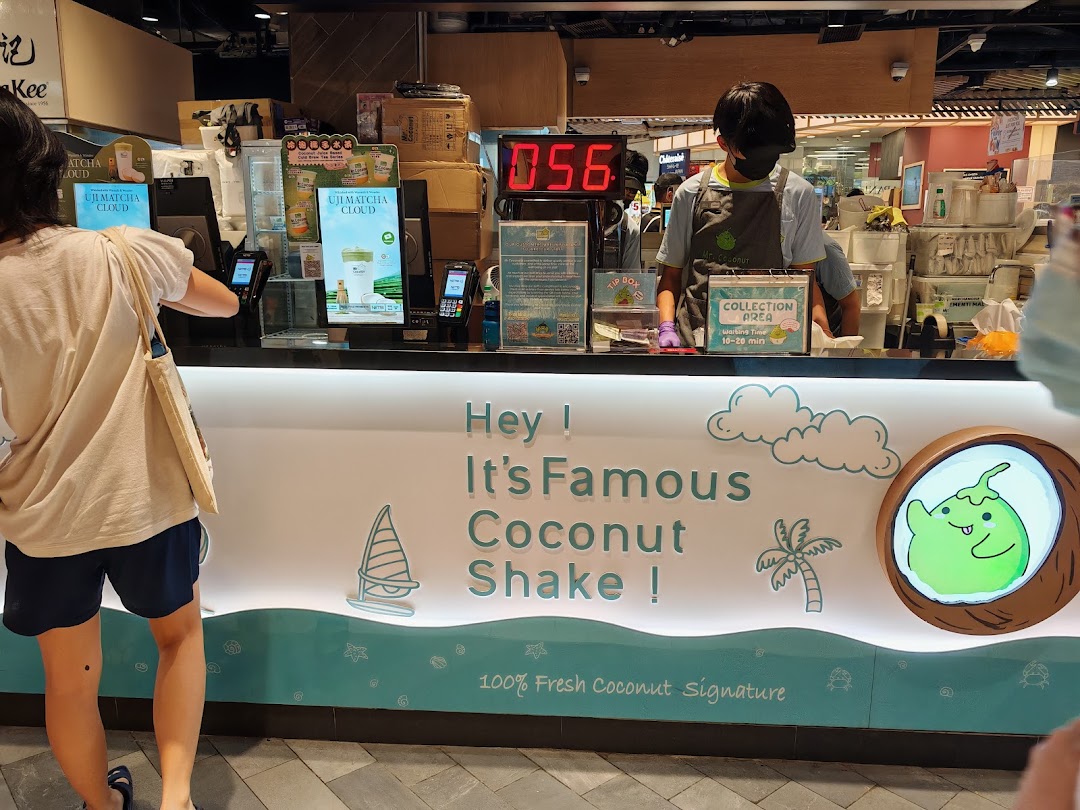 A customer at the counter of Mr Coconut, featuring the shop's branding and a staff member.