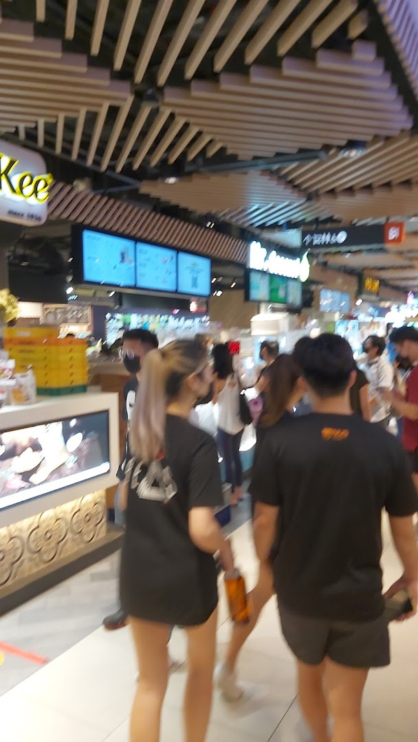 Shoppers walk past Mr Coconut and other food stalls in a bustling mall environment.