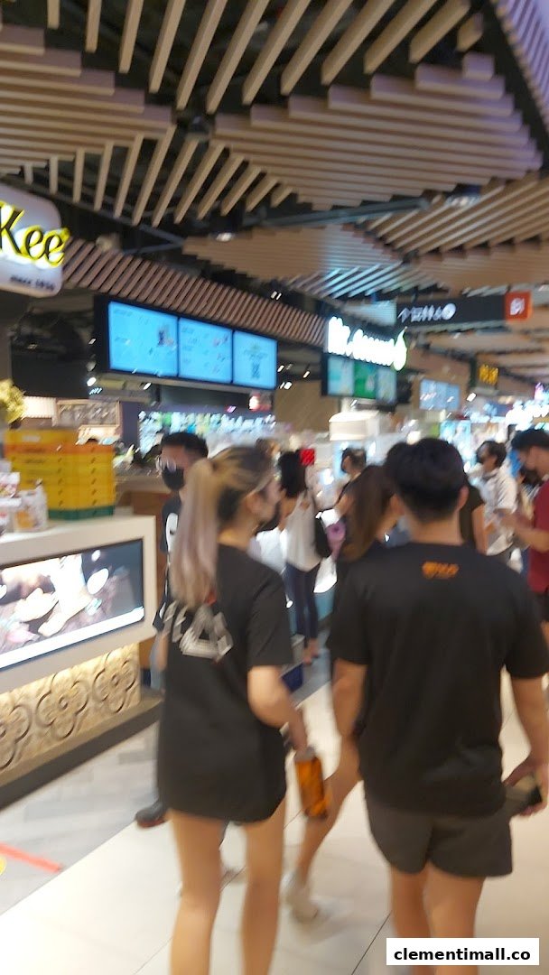 Shoppers walk past Mr Coconut and other food stalls in a bustling mall environment.