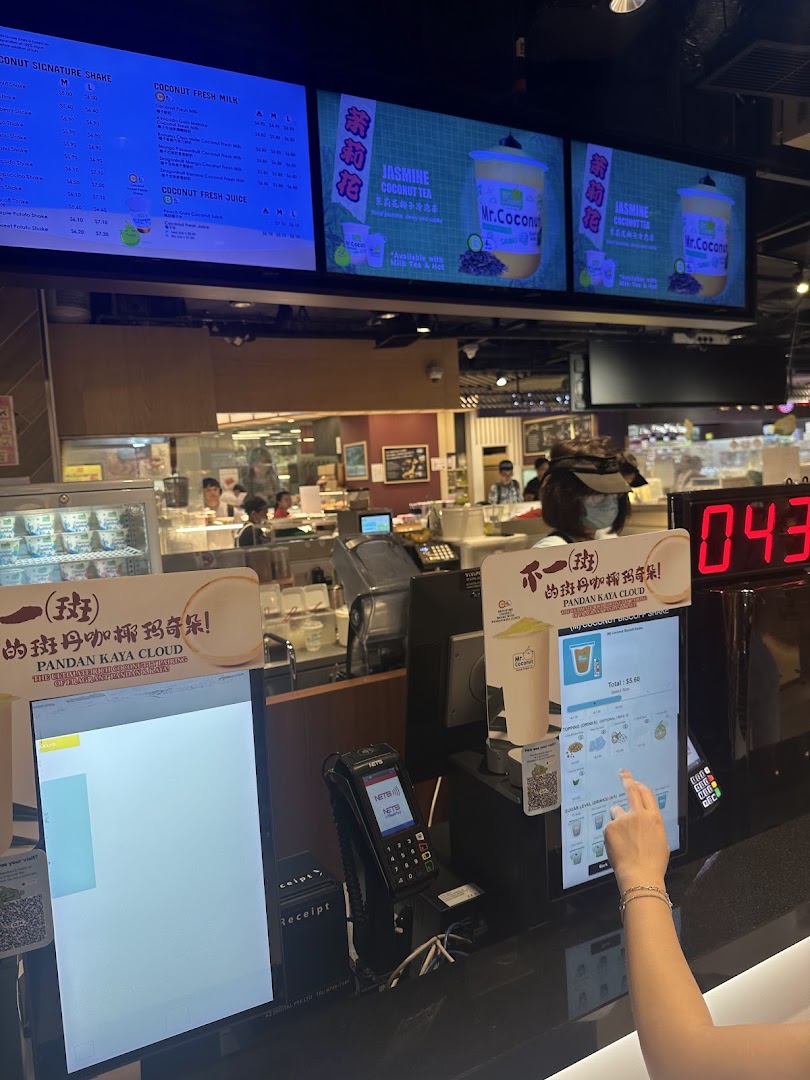 Digital menu boards and self-service kiosk at Mr Coconut, showcasing various coconut beverages.