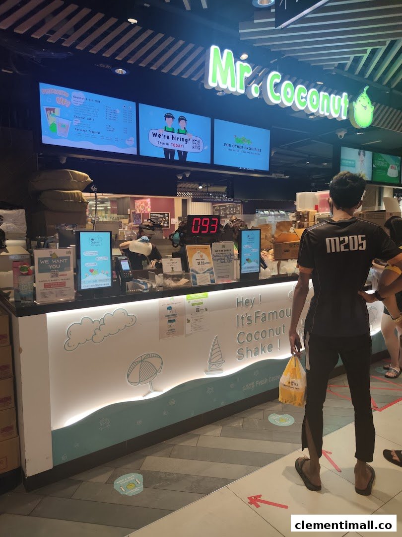 A vibrant view of the Mr Coconut shop counter with a staff member and digital menu boards.