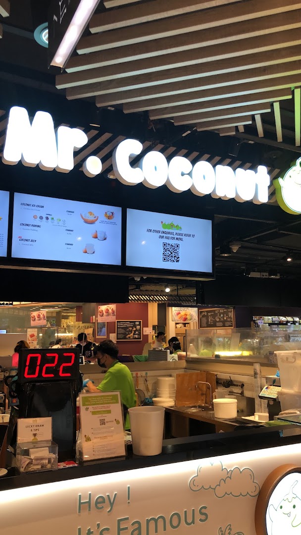 An interior shot of Mr Coconut, featuring the service counter, staff, and digital menu displays.
