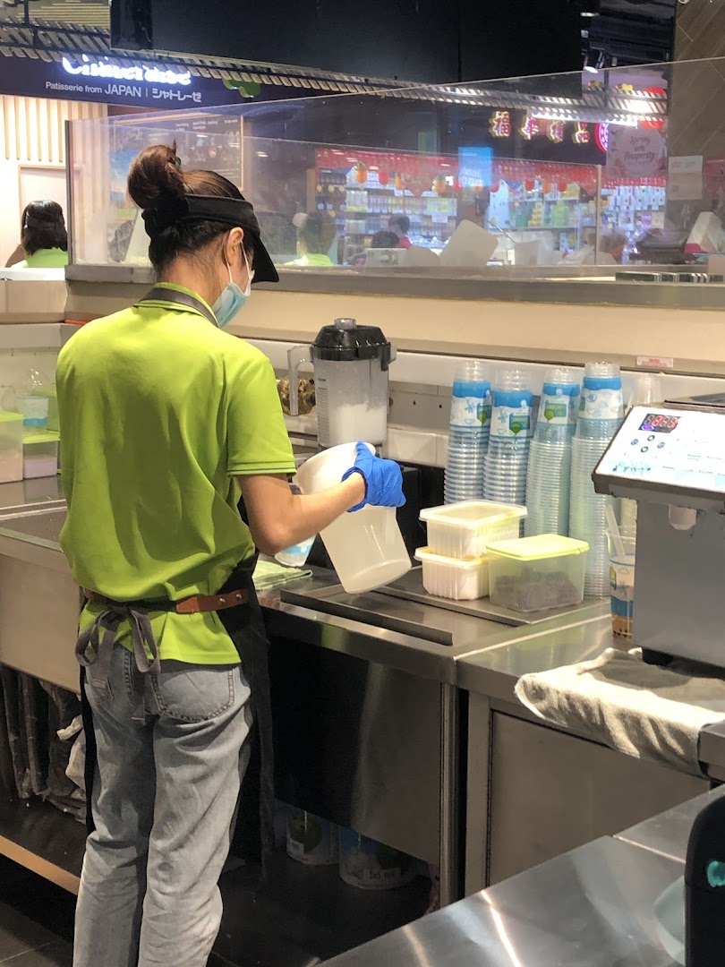 A Mr Coconut staff member in a green uniform prepares drinks behind a stainless steel counter.