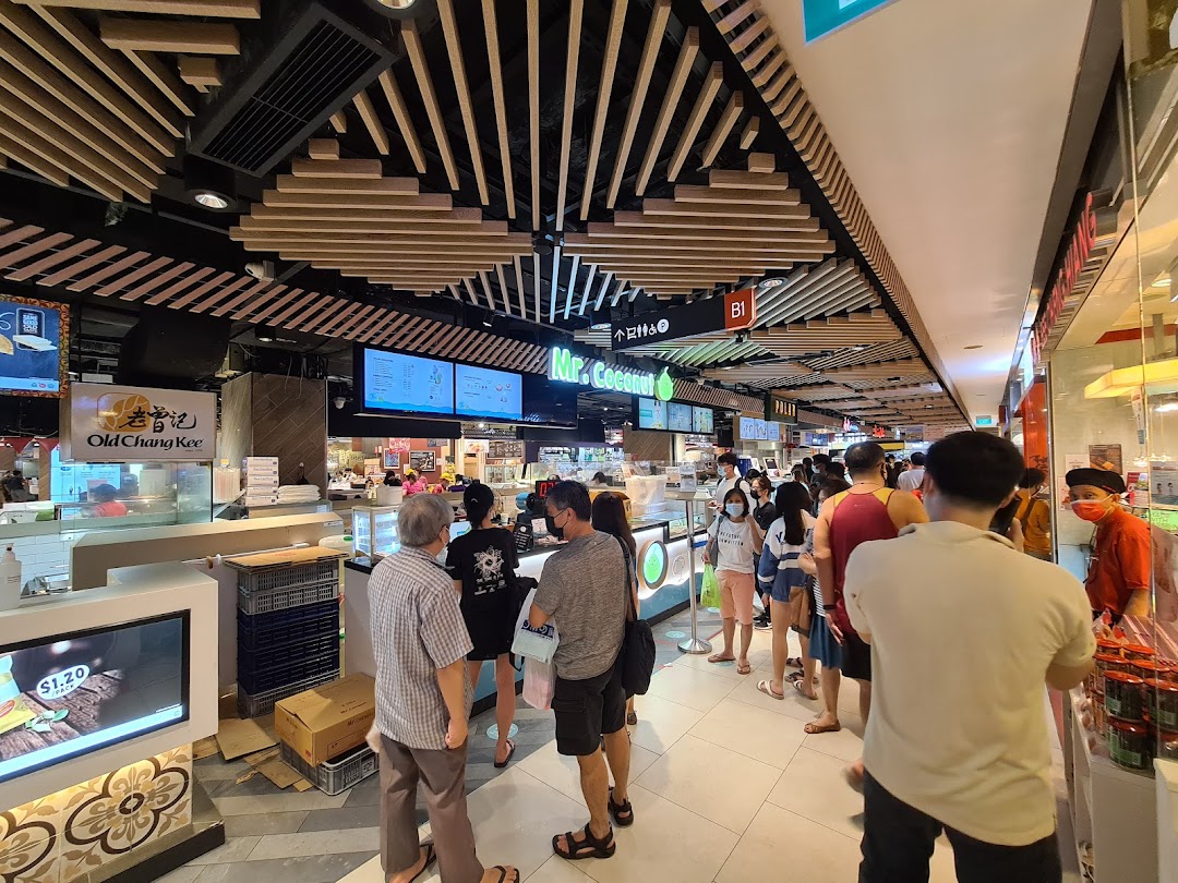 Customers queueing at popular food stalls, including Mr Coconut, in a busy shopping mall food court.