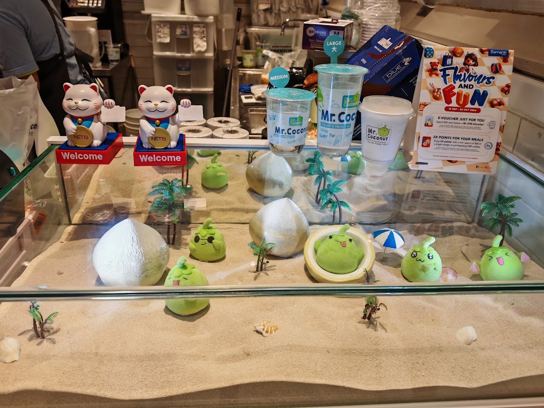 A vibrant display case at Mr Coconut featuring sand, decorative coconuts, and brand merchandise.