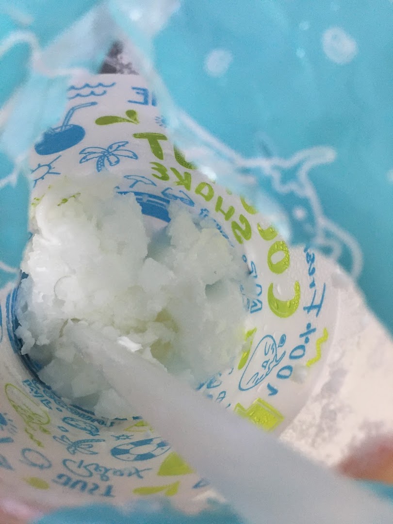 A close-up of a refreshing coconut-based dessert in a branded cup with a spoon.