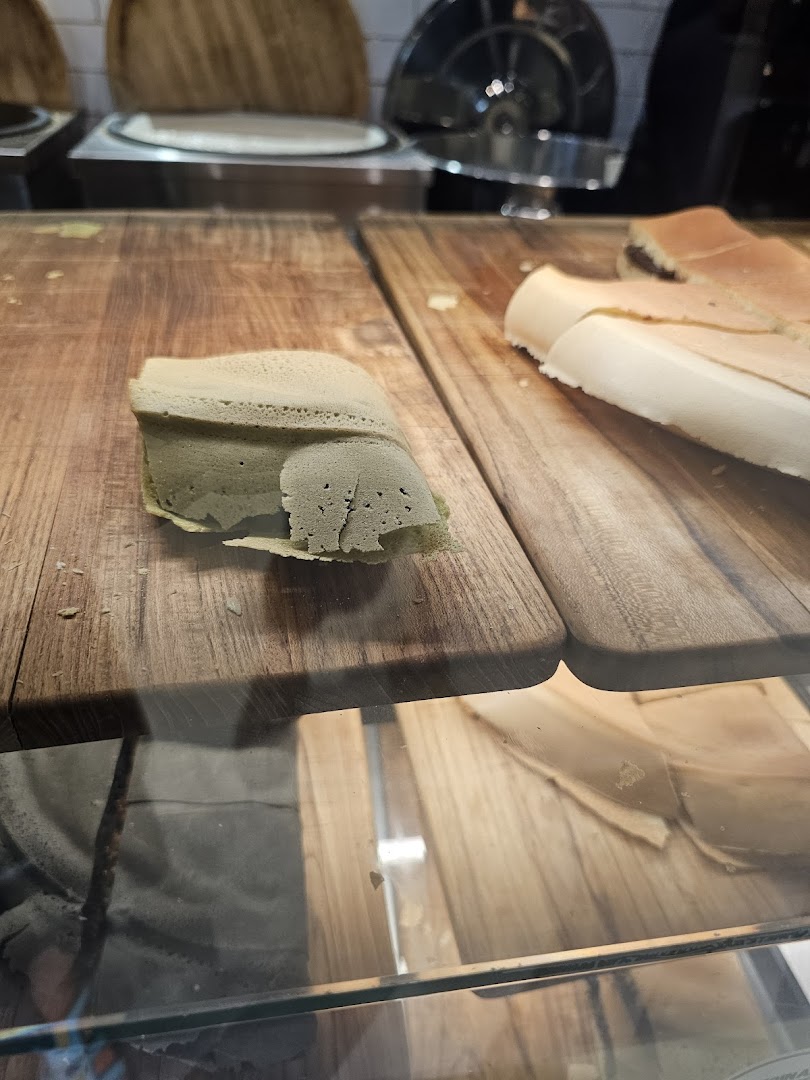 Close-up of freshly made Munchi Pancakes, including a green tea flavored one, displayed on wooden boards.