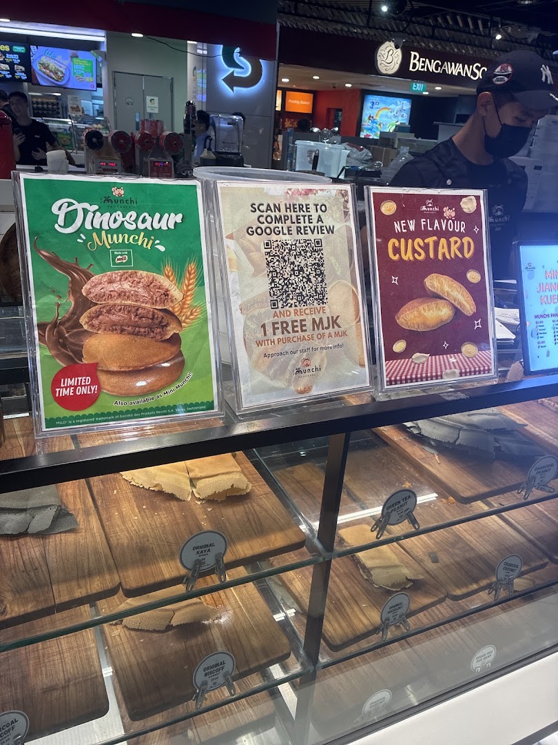 A vibrant display counter at Munchi Pancakes showcasing promotional signs for new flavors and a customer review offer.