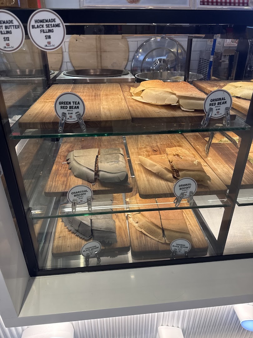 A display case at Munchi Pancakes showcasing various pancake flavors and fillings with prices.