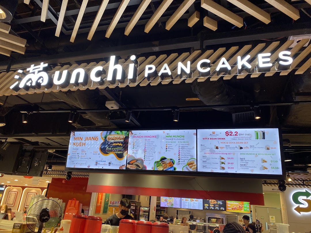 A digital menu board displaying various pancake and soya bean drink options at Munchi Pancakes.
