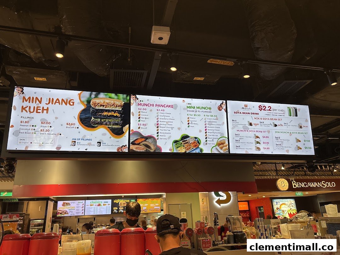 A brightly lit digital menu board for Munchi Pancakes, displaying various pancake and soya bean drink options.