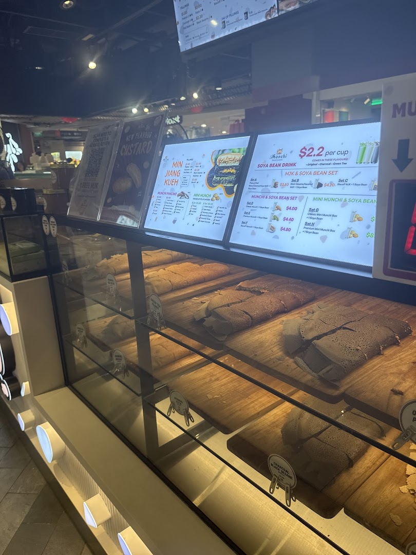 A display case showcasing various Munchi pancakes with illuminated menu boards in the background.