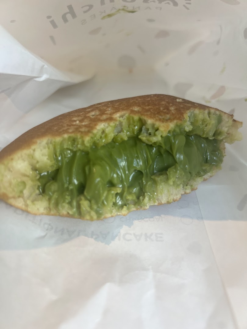 A close-up of a Munchi pancake filled with a vibrant green, creamy filling, likely matcha.