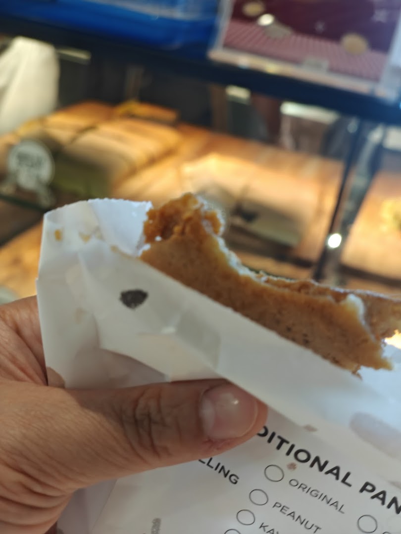 A hand holds a delicious Munchi pancake, with more treats visible in the background display.