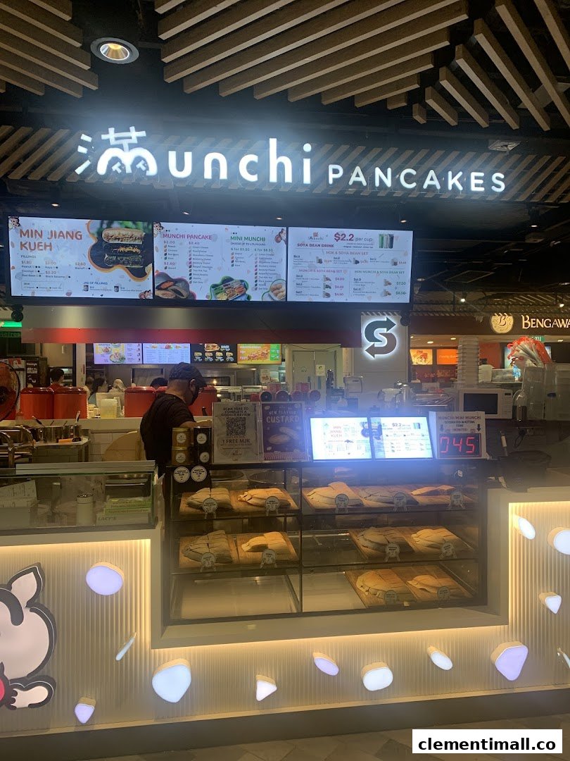 A brightly lit Munchi Pancakes shop front showcasing its digital menu board and fresh pancake display.
