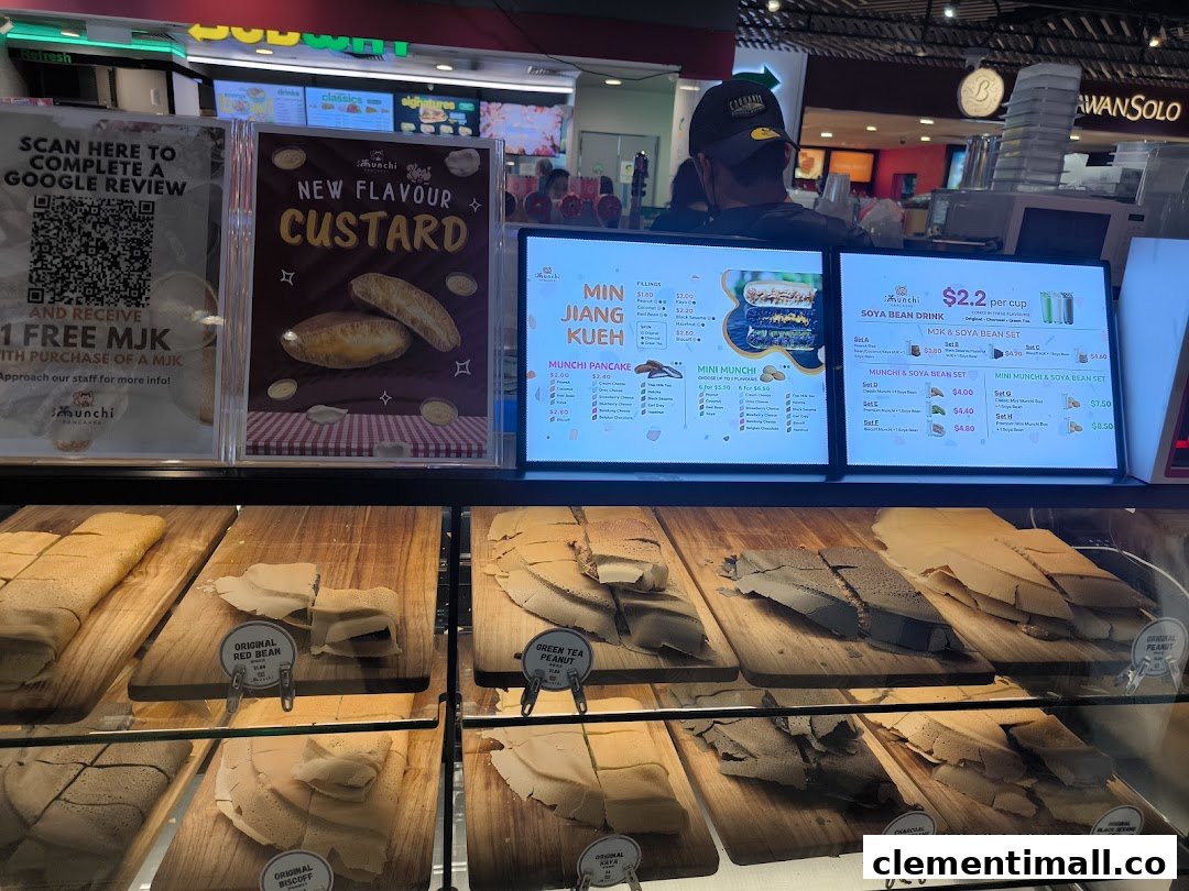 A display counter at Munchi Pancakes showcasing various pancakes and digital menu screens with prices.
