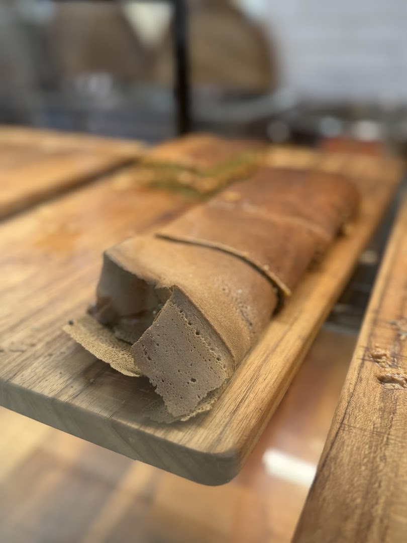 A large, rolled pancake with a thick filling, displayed on a wooden board.