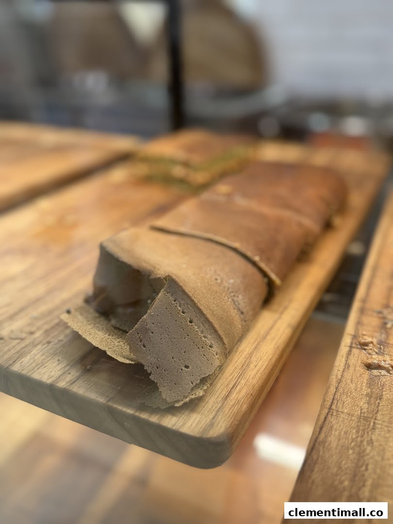 A large, rolled pancake with a thick filling, displayed on a wooden board.