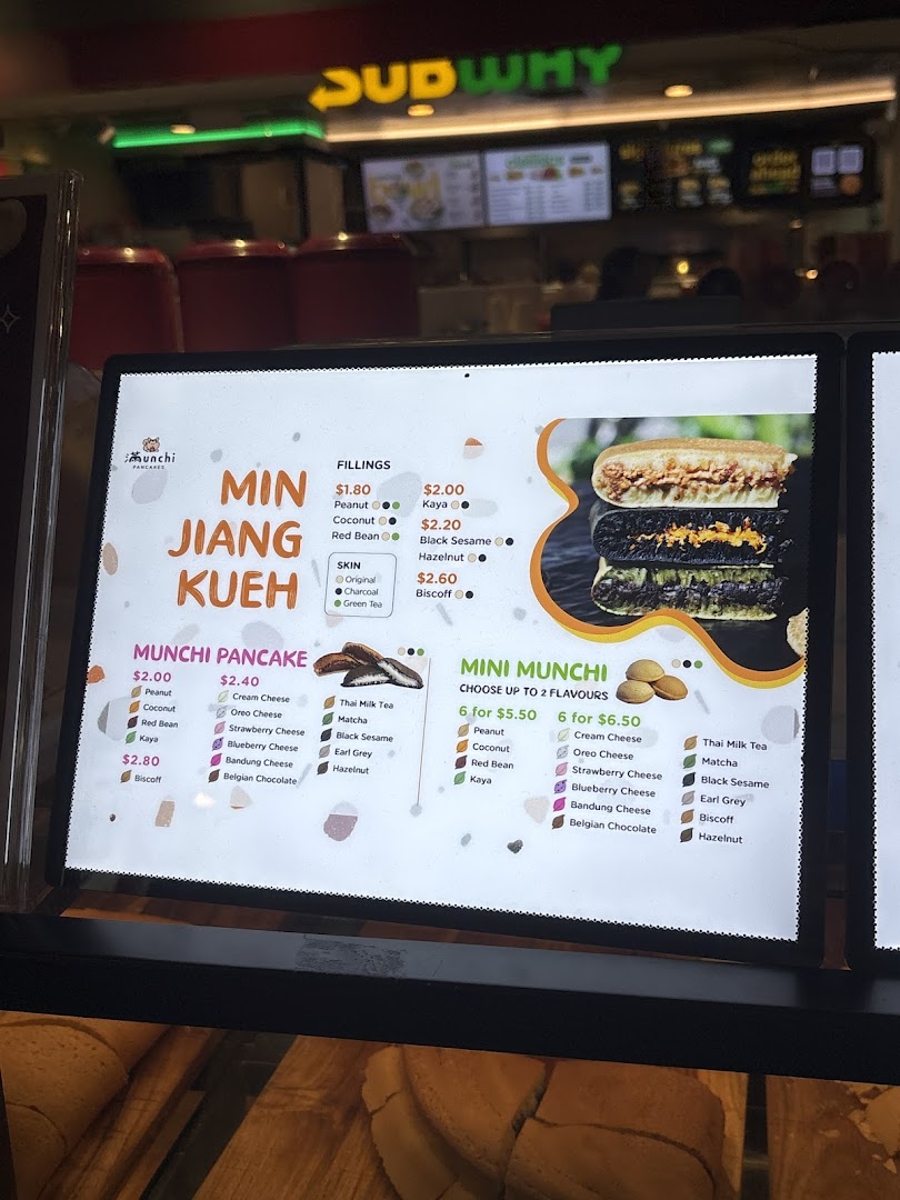 A digital menu board for Munchi Pancakes, displaying various pancake types, fillings, and prices.