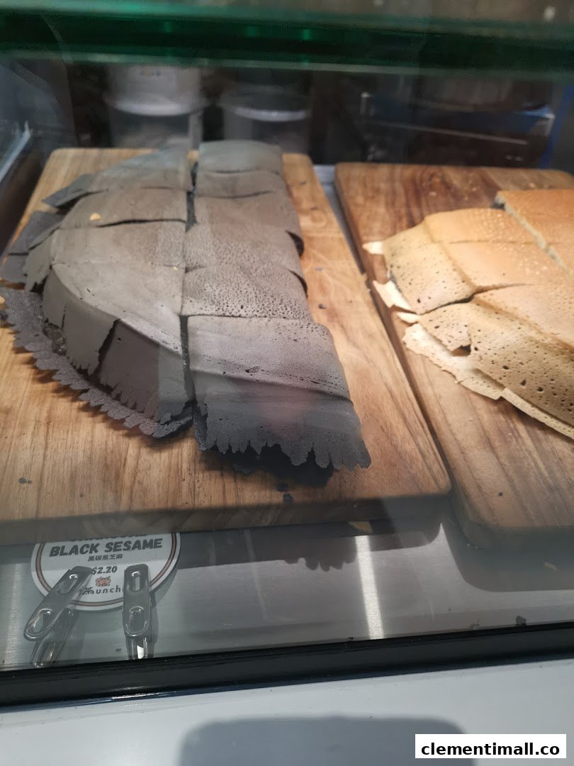 Close-up of black sesame and traditional pancakes displayed on wooden boards in a glass case.