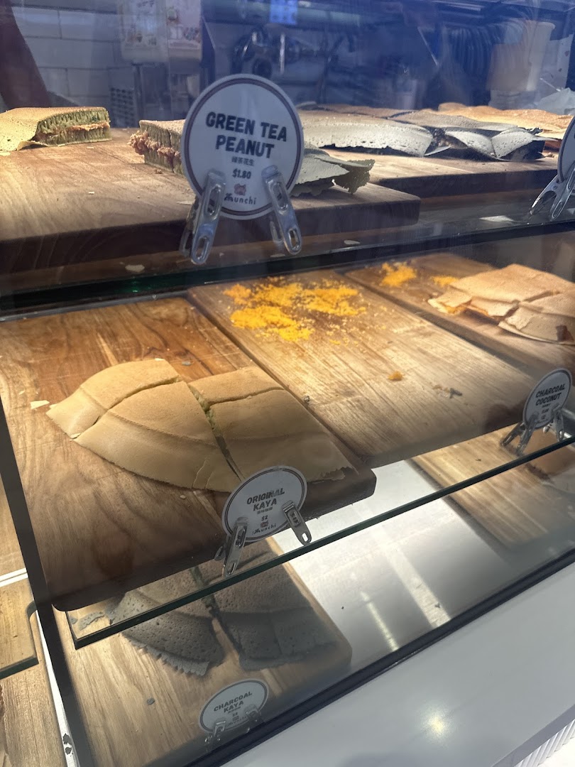 A display case showcasing various Munchi Pancakes flavors like Green Tea Peanut, Original Kaya, and Charcoal Coconut.