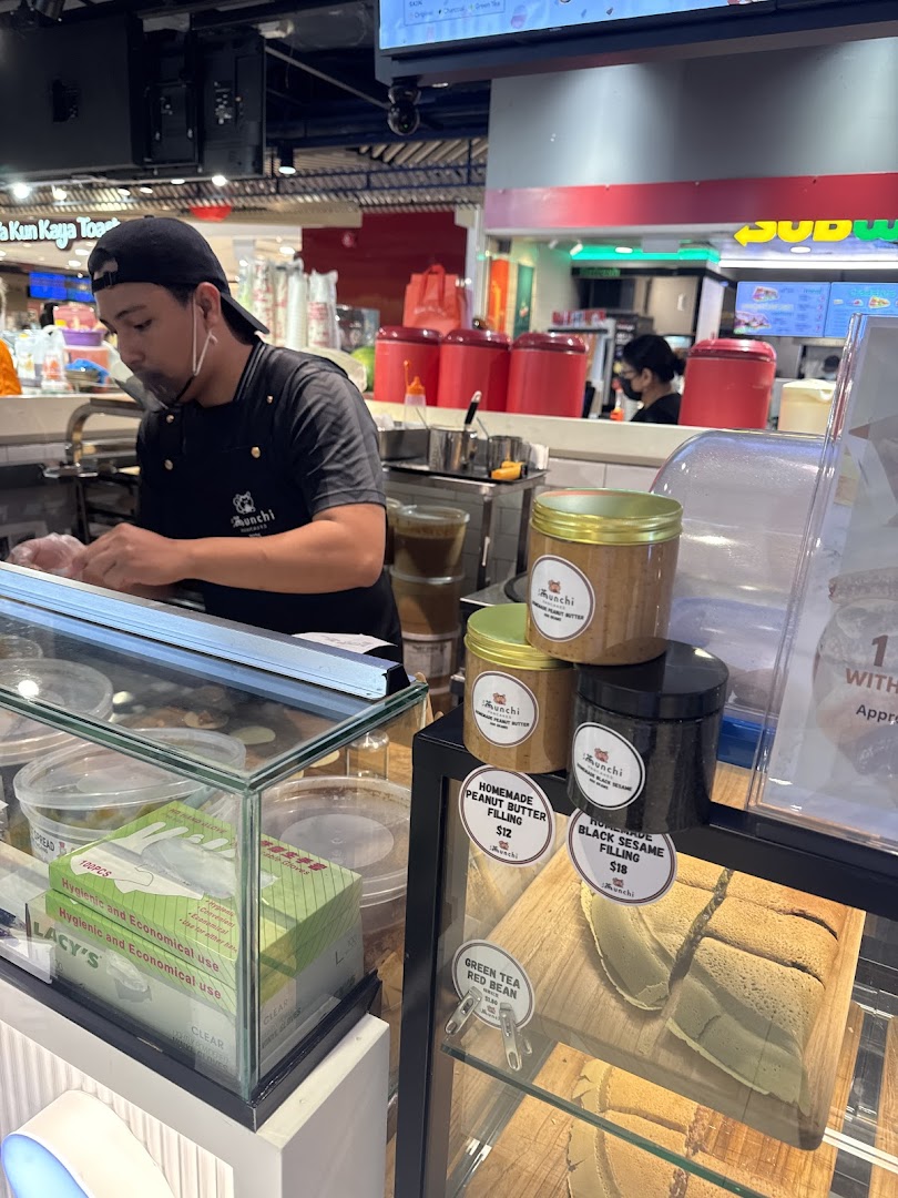 A staff member at Munchi Pancakes prepares fresh items, showcasing delicious pancake fillings and products.