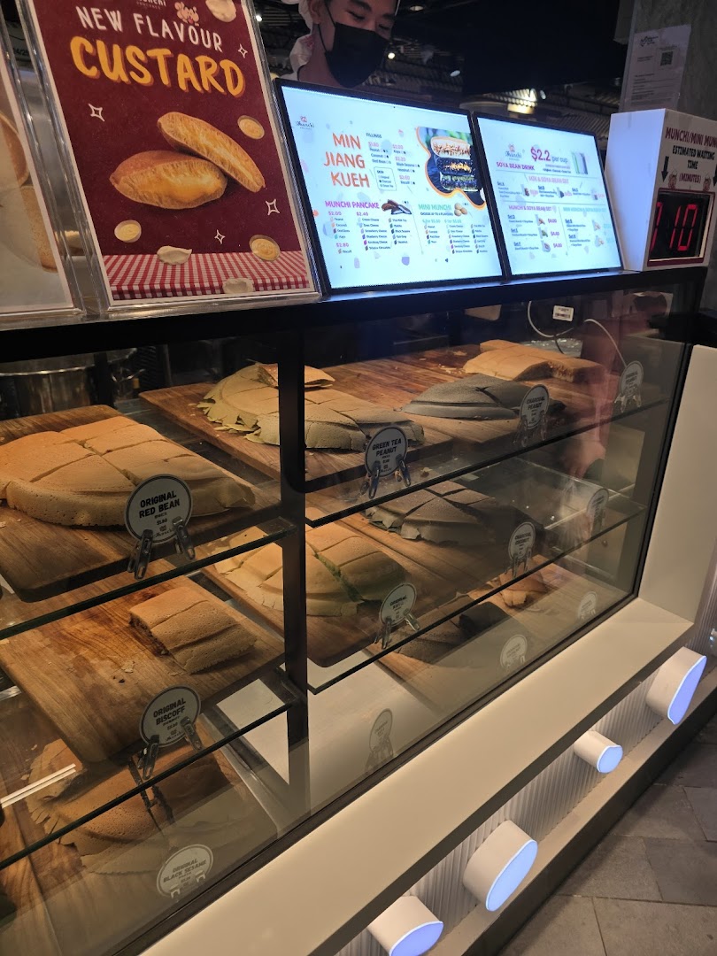 A vibrant display of freshly made Munchi Pancakes and digital menu boards showcasing various flavors and drinks.