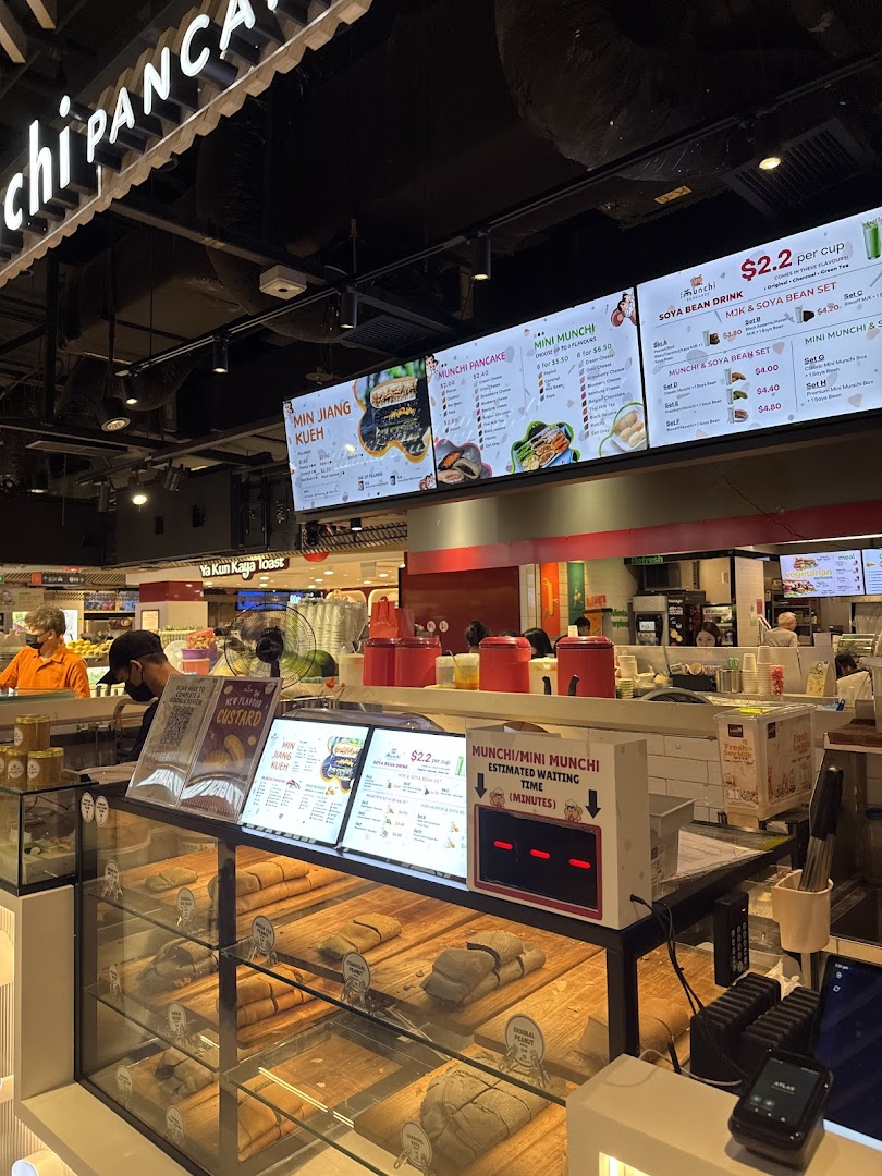 A vibrant view of Munchi Pancakes' counter, showcasing fresh pancakes, digital menus, and a waiting time display.