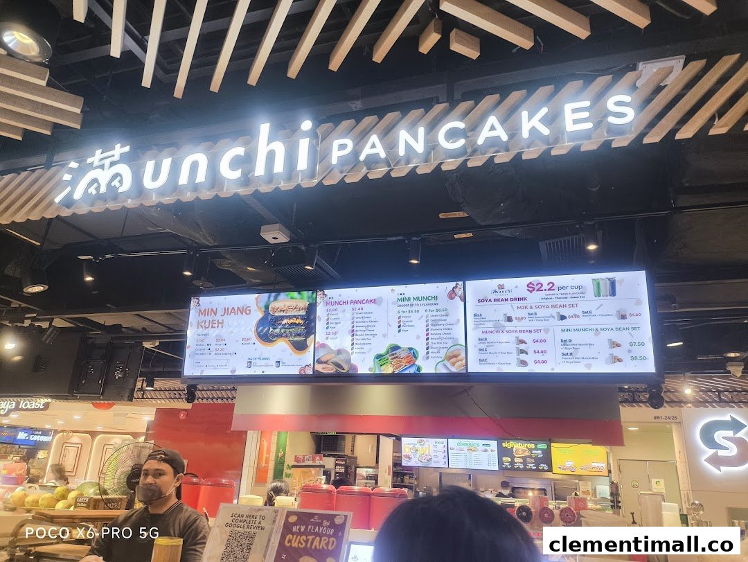 A vibrant shot of Munchi Pancakes' counter, featuring their bright digital menu board and a staff member.