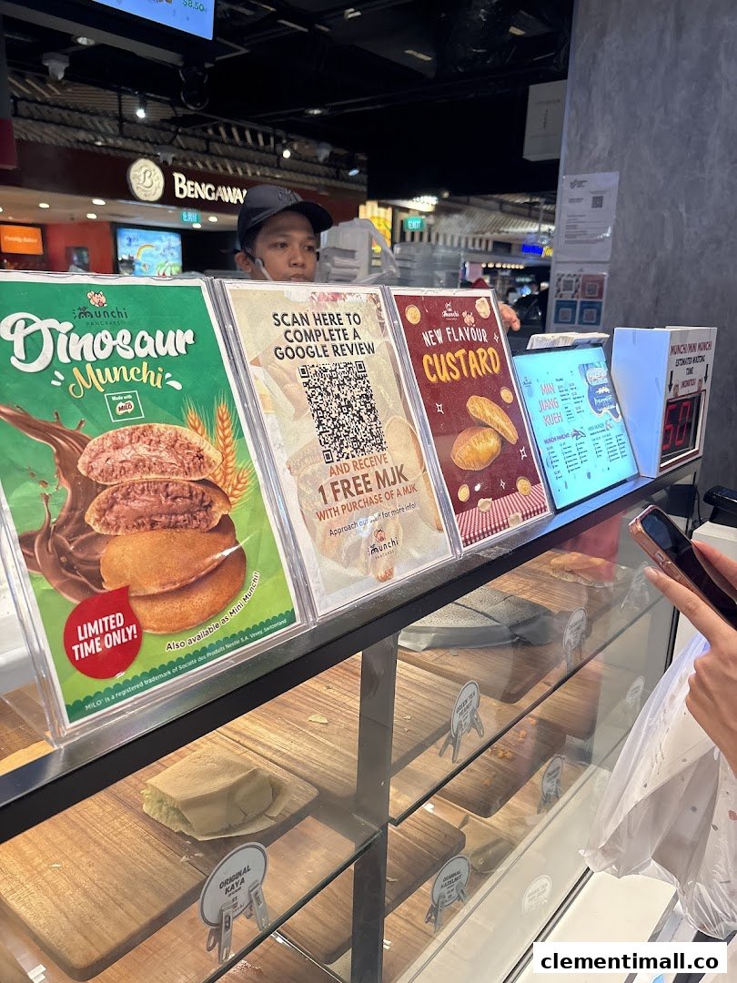 A staff member stands behind the counter of Munchi Pancakes, showcasing promotional displays and a product display case.