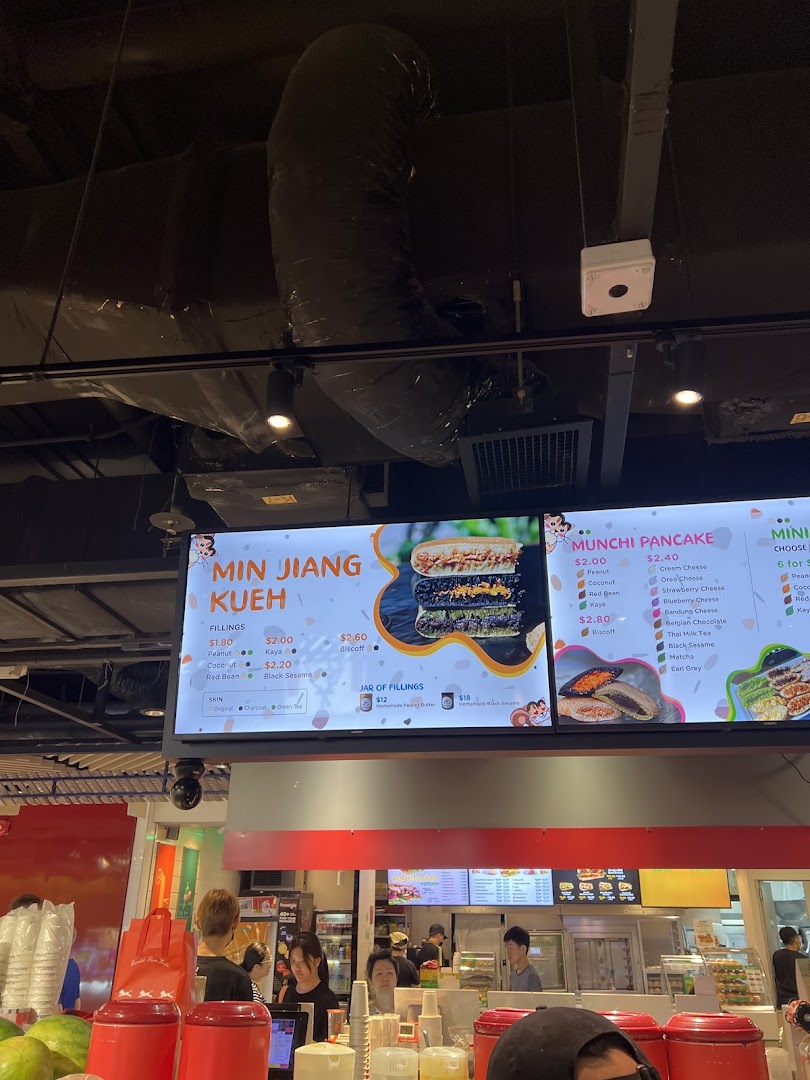 A digital menu board displaying various pancake and kueh options with prices at Munchi Pancakes.