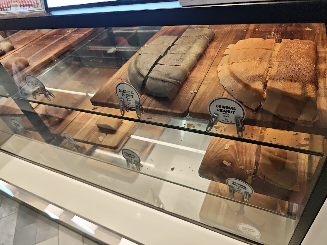A vibrant display case showcasing various freshly made Munchi Pancakes, including Original Peanut and Charcoal Peanut.