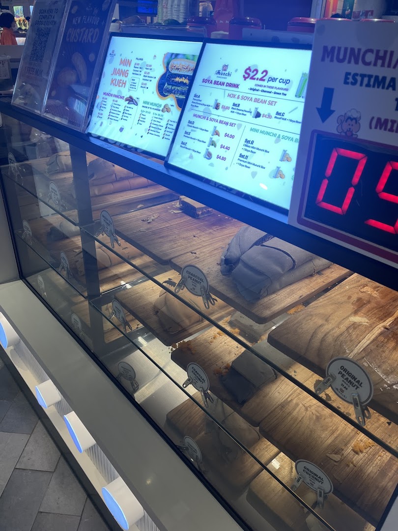 A display case showcasing pancakes and prominent menu boards for Munchi Pancakes, detailing various flavors and sets.